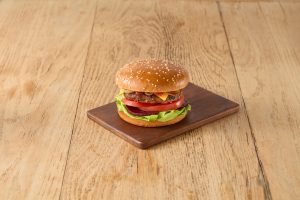 Classic Aussie beef burger with cheese, lettuce, tomato and beetroot made with Tip Top Grill House Classic Burger Buns on a wooden board.